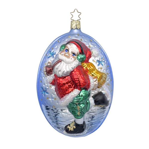 A glass ornament featuring an ice skating Santa Claus with red and green attire on a blue background with a gold star top for hanging by Inge Glas of Germany