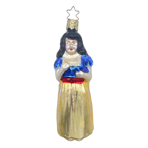 A glass ornament featuring a fairy tale princess with black hair, wearing a blue and white dress with a red scarf, standing with her hands at her sides. This ornament is mouth blown glass and hand painted by Inge Glas of Germany.