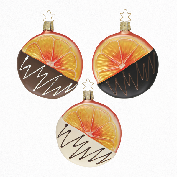 Three round Christmas ornaments with orange slice design dipped in chocolate with a gold star top for hanging on a white background