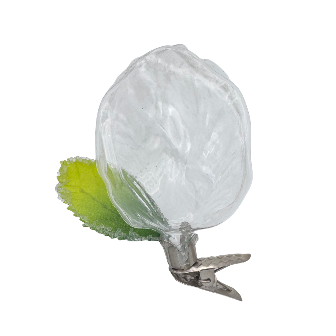 Clear glass tulip shaped ornament with a green leaf attached to a metal clip for hanging on a white background