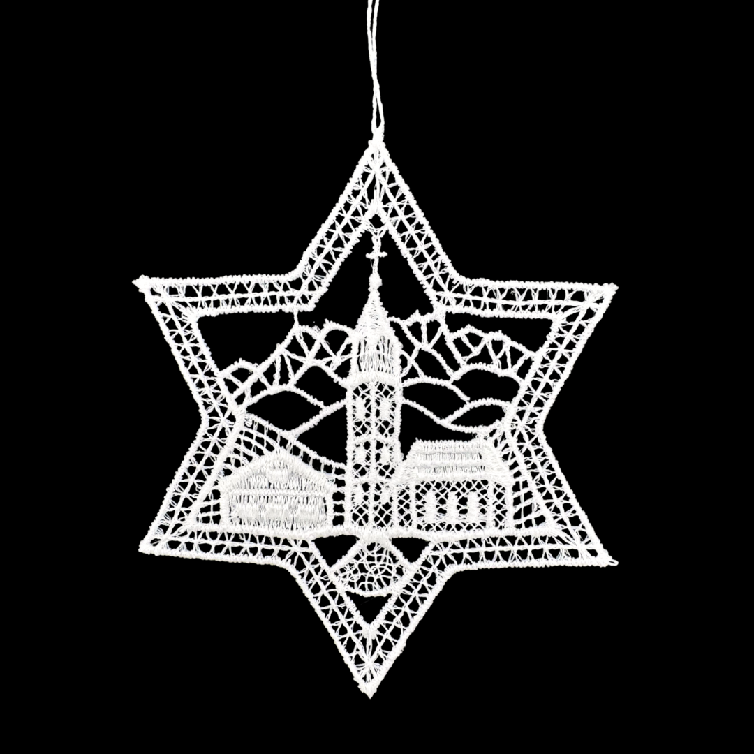 Decorative white star-shaped lace ornament with a scenic church and landscape design in the middle, on a black background