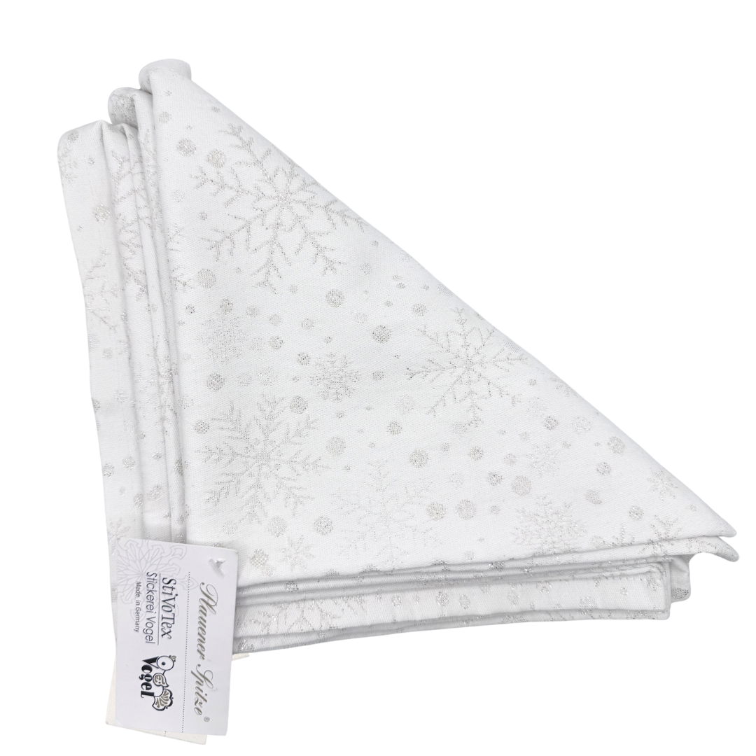 Folded white napkins, in a triangular shape with silver snowflake and dots pattern on a white background