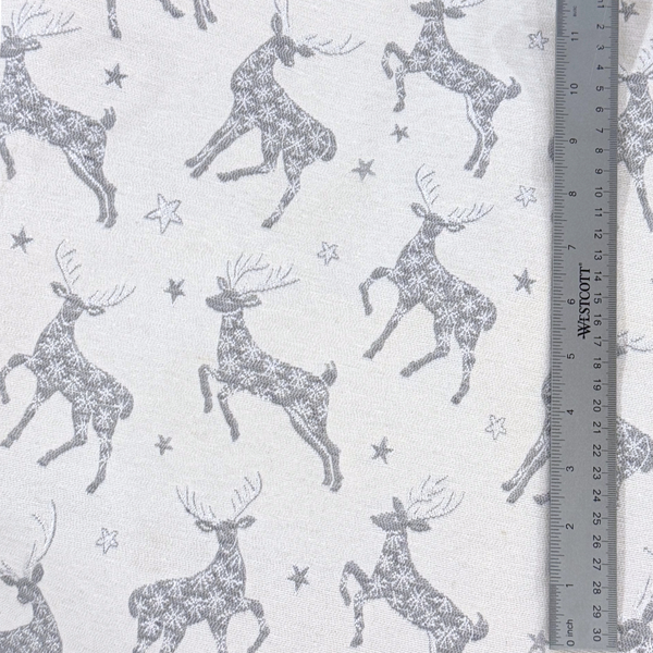 Close up pattern of stags and stars in a dark silvery gray on a light gray background with a ruler to show scale.
