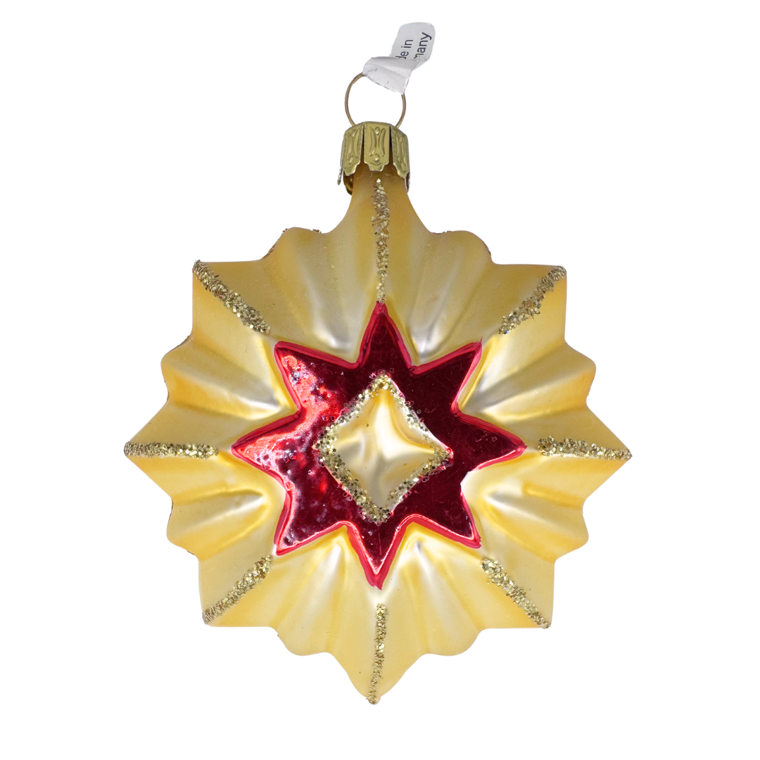 Decorative star ornament with red center and gold accents on a white background