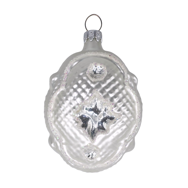 Decorative glass ornament in the shape of a Victorian pillow with scalloped edges and a star design in the center on a white background