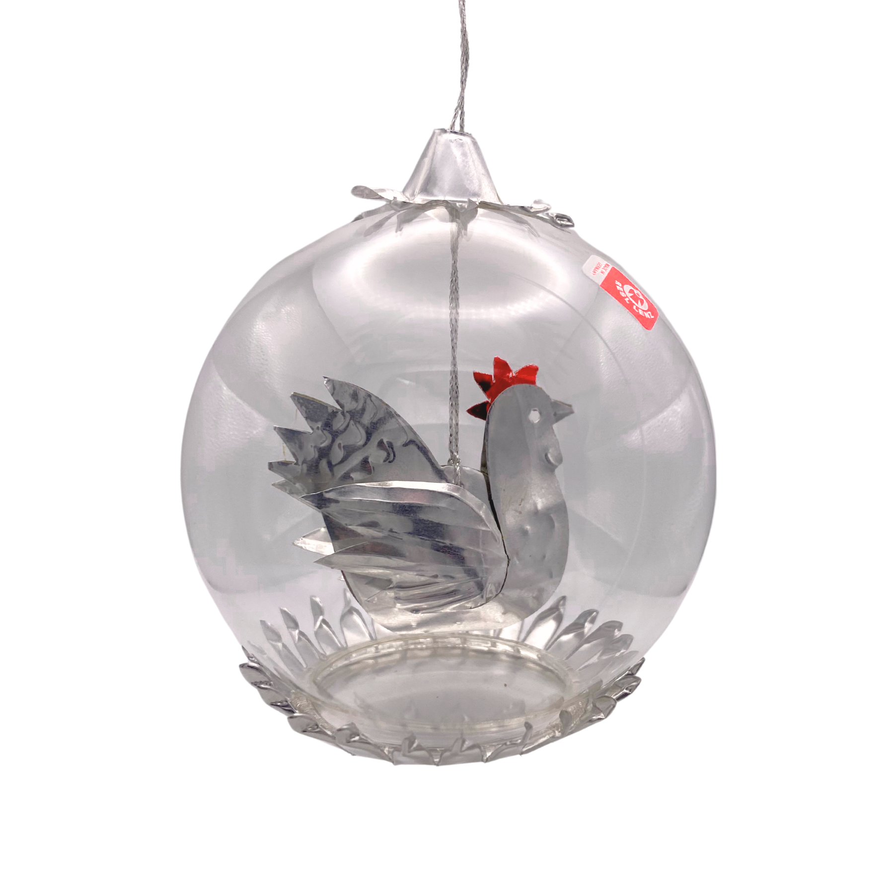 A hanging clear glass ornament shaped like a bowl, containing a gray metal rooster with a red comb, suspended against a plain white background.