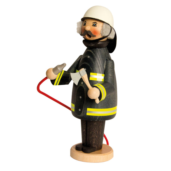 Wooden firefighter incense smoker holding an axe and hose in a black coat and wearing a white helmet by Kuhnert GmbH