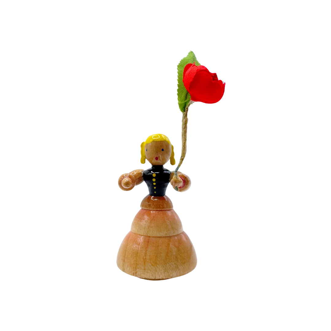Wooden figurine of a girl holding a red flower on a white background by Inge Glas of Germany
