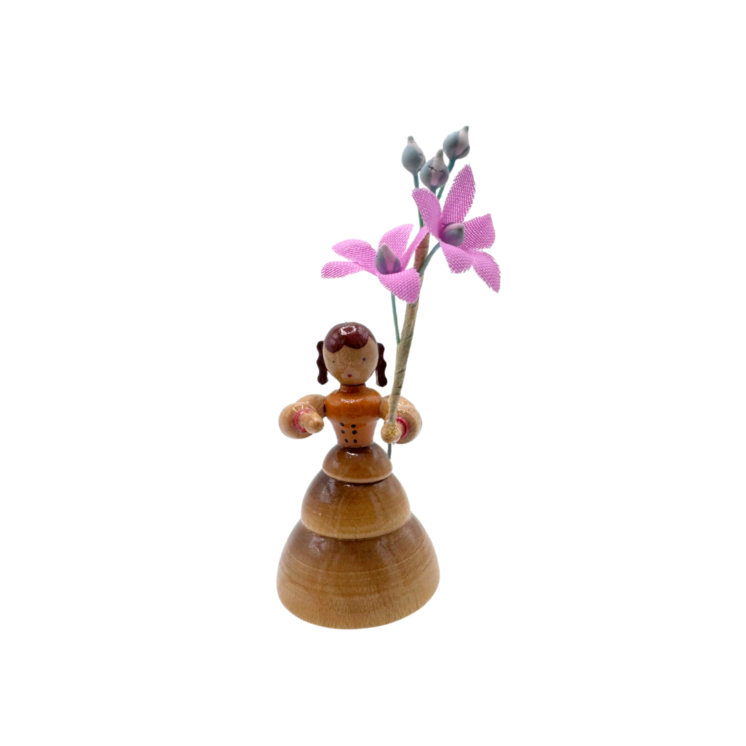 Wooden figurine of a girl holding pink flowers on a white background by Inge Glas of Germany