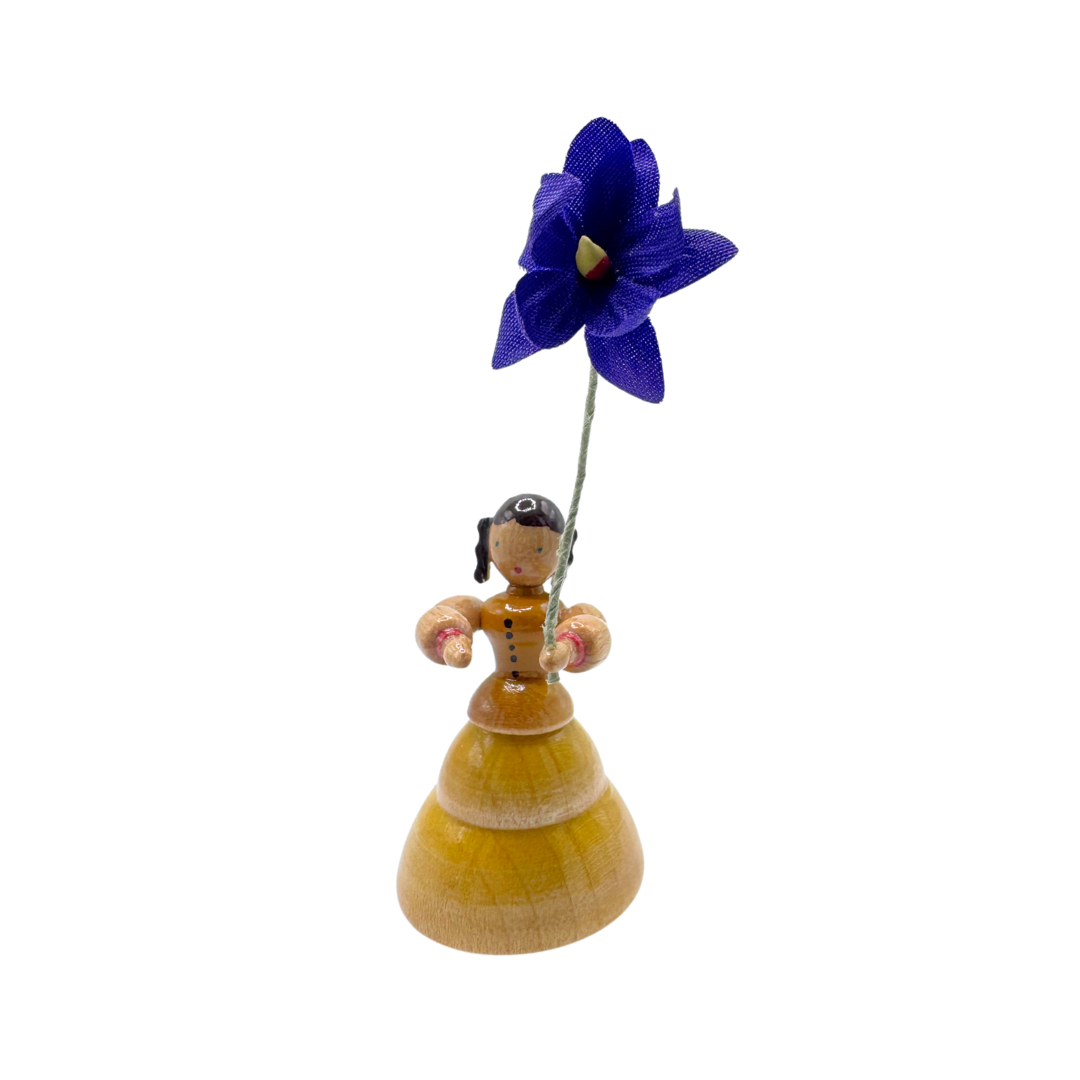 Decorative figure of a woman holding a purple flower on a white background by Inge Glas of Germany