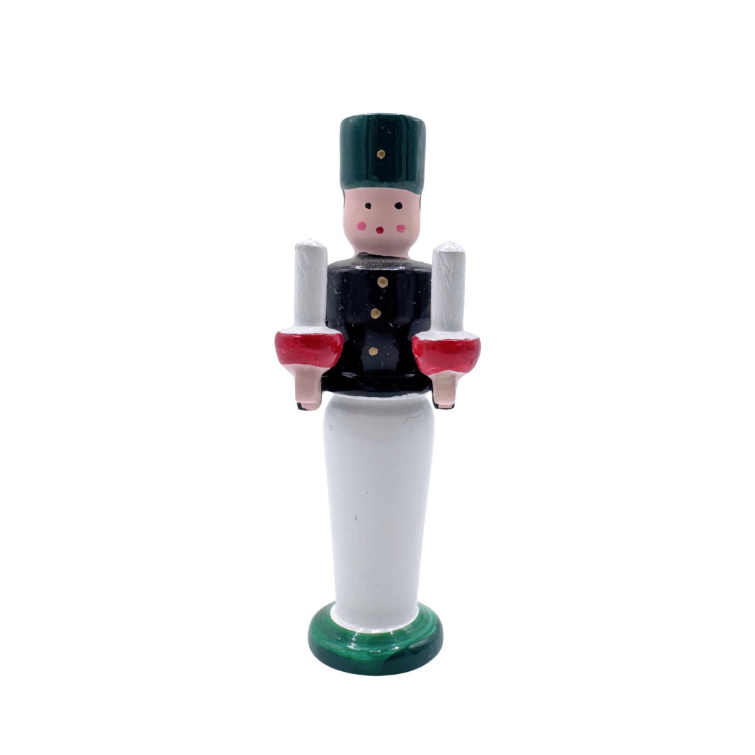 Wooden miniature figurine  of a miner with black and white attire, holding two wood candles on a white background