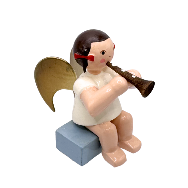 Miniature figure of a sitting angel with gold wings playing a flute on a blue base