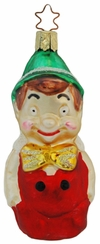 A glass ornament depicting a stylized version of Pinocchio, with a green hat and a red and gold coat, designed by Inge Glas of Germany.