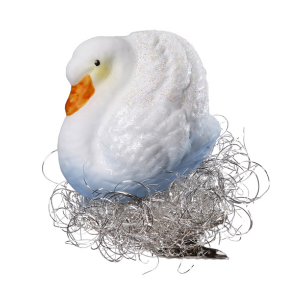 A white glass swan ornament with orange beak and silver metallic nest.