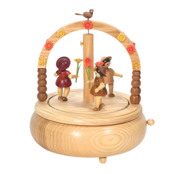 Round natural wood music box with a flower arch and children playing underneath.